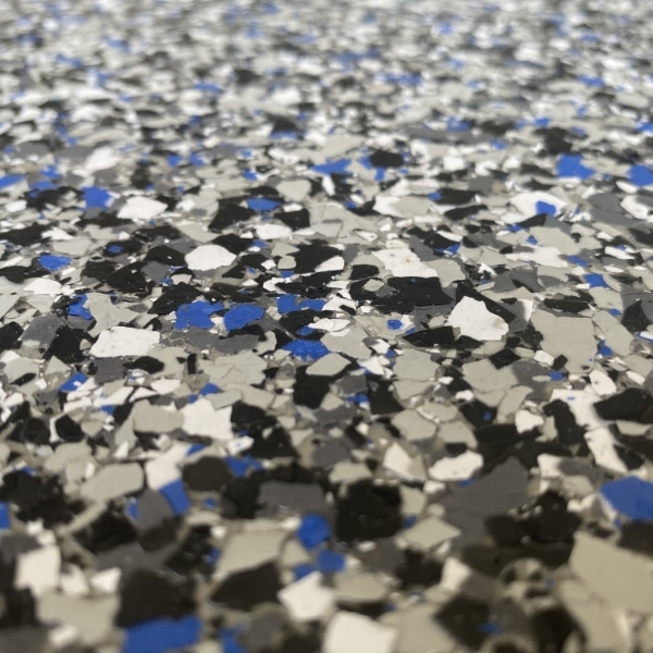 The image shows a close-up of a speckled surface with a mix of black, white, and blue fragments, possibly a textured floor or countertop material.